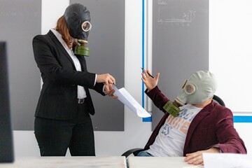 Man and woman working on a computer in the office, businesspeople in a suit with gas mask against...