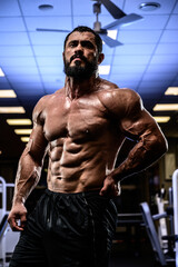 Fototapeta na wymiar active strong man with beard and perfect abdominal muscle during heavy workout training in night sport fitness gym