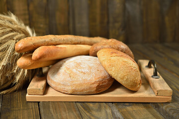 Different breads on cutting board on a wooden background
