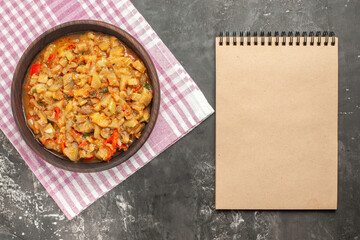 top view roasted eggplant salad in bowl a notebook on dark background