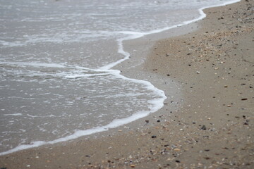 A wave rolls over the sandy shore. The winter sea.