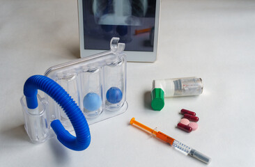 Fototapeta na wymiar Spirometer, inhaler and medications for respiratory failure, chest x-ray in the background