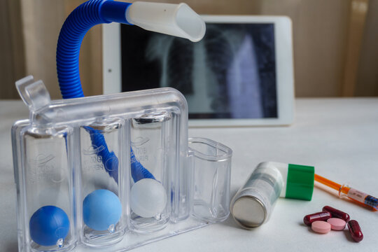 Spirometer, inhaler and medications for respiratory failure, chest x-ray in the background