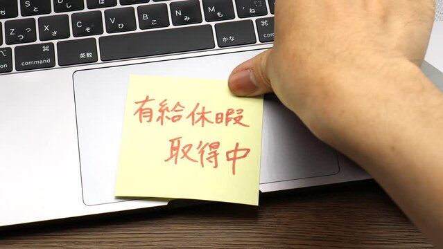 ノートパソコンに有給休暇取得中と書かれた付箋を貼りつける