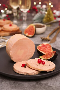 A traditional French whole duck foie gras with a sliced pieces on a plate with fig fruit. Glasses of Champagne in background with Christmas decoration and celebration atmosphere