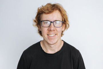 Portrait of a red-haired man with glasses smiling on a white background in a black T-shirt