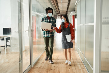 Smiling motivated student man holding laptop and chatting with group mate