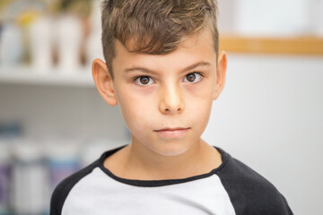 Boy in black and white t-shirt with dark hair looking at the camera