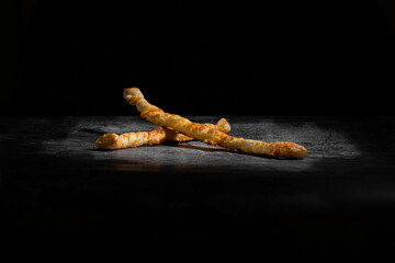 Cheese bread sticks, baked on a dark gray background.