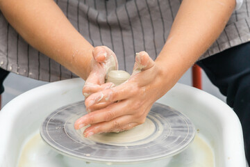 Potter woman's hands sculpt clay on a potter's wheel