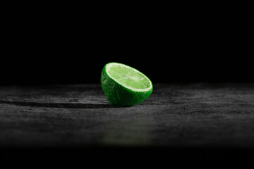 Gray textured board with laim in the middle of dark background.