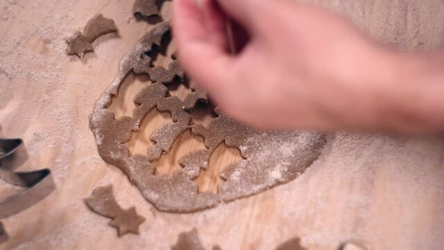 Person preparing gingerbread cookies for Christmas. Cutting starts, reindeers, christmas trees and gingerbread men.