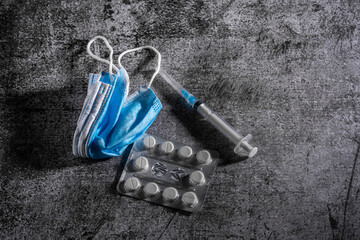 Face mask, syringe, pills on dark background. Medicine and healthcare. Medications and pharmacy.