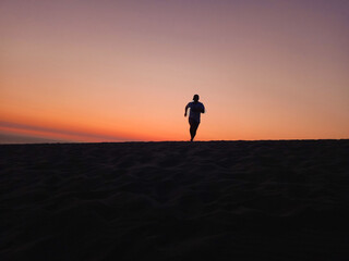 Fototapeta na wymiar the man run at sand dunes when sunset time. 