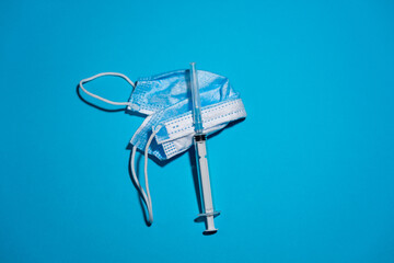 Blue medicine mask and syringe on blue background.