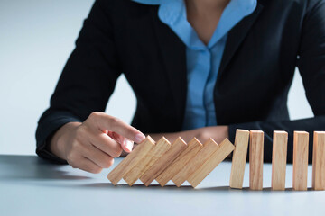 businessman hand taking Falling wooden Dominoes effect from continuous toppled or risk, strategy...