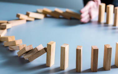 Businessman hand stop dominoes continuous toppled or risk with copyspace. Business risk, strategy and planing concept idea.