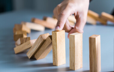 Chain Reaction In Business Concept, Businessman Letting Or Preventing Dominoes Continuous Toppling On Rustic Wooden Desk