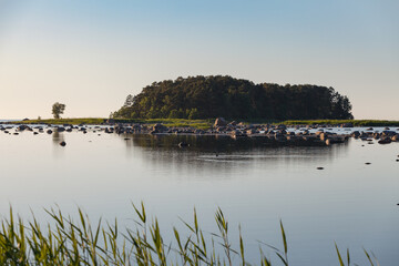 Obraz premium Stony shore of Baltic sea and small island at sunset