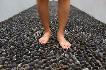 Cropped image woman feet walking on cobble pavement, healthy lifestyle, reflexology