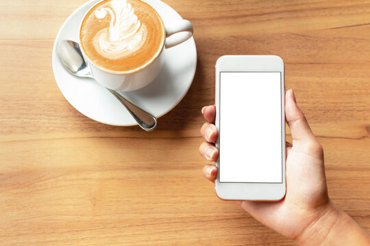 Mockup image of hands holding white mobile phone with blank white screen with Modern coffee shop with coffee  for input the text on copy space Top view, flat lay.