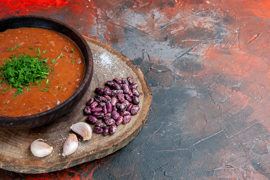 Half shot of tomato soup beans garlic on wooden cutting board on mix color background stock image
