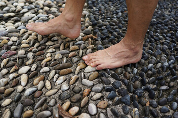 Cropped image man feet walking on cobble pavement, healthy lifestyle, reflexology