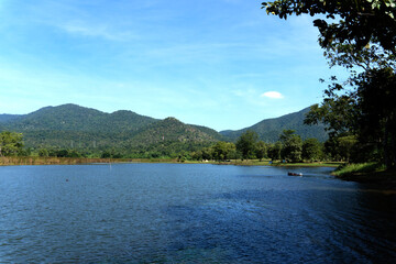 Fototapeta premium Landscape of the mountains and river near the dam with natural summer day light blue sky with clouds in the background, the shadow over the branches tree