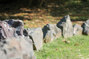 black stones on a meadow stacked in circles, a human work
