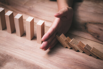 Wooden game strategy, Businessman hand stopping risk falling wooden dominoes effect Create stability for the company