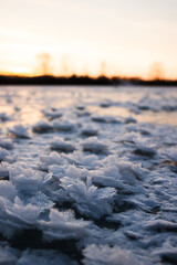 Frozen ice with beautiful snow crystals on a sunset
