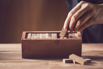 hand man pick one  domino wood block choosing the right amongst Human resource, strategy ,Planning,risk