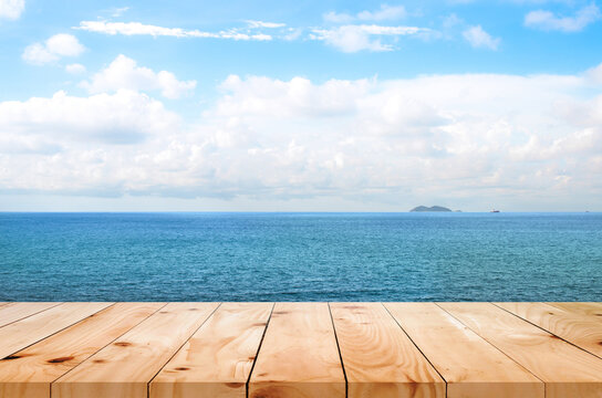 image of Wooden table in front of blue sea and bright landscape