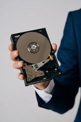 Obraz premium business man holding disassembled hard drive on gray background