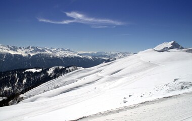 Fototapeta na wymiar Winter landscape with mountain peaks, gorges, deep snow cover, ski slopes.