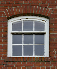 Nine pain glass window set in a red brick wall