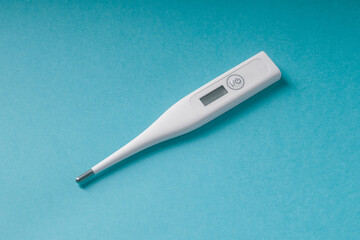 Electronic white thermometer, on a blue background, side view