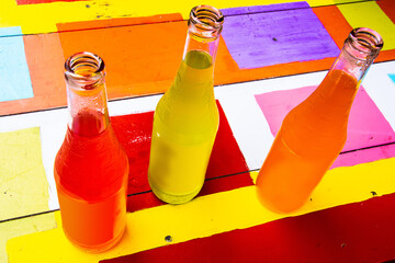 three bottles of soda on a colorful table