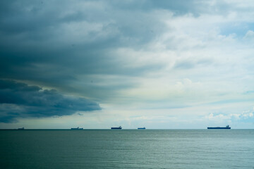 Seaview with ships in Port Dickson. Heavy clouds in the rainy season. The image contains soft focus, noise and grain.