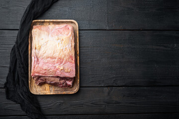 Strip steak, marbled beef meat, on black wooden table, on black wooden table, top view, with copy space for text