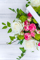 Wooden box with white and pink roses and chrysanthemums on  white wooden board. Decoration of home. Flowers boxes. Wedding decoration