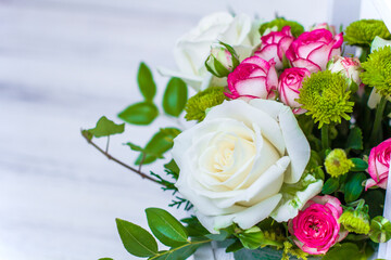 Wooden box with white and pink roses and chrysanthemums on  white wooden board. Decoration of home. Flowers boxes. Wedding decoration