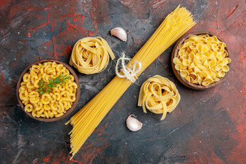 Overhead view of various types of uncooked pastas on mixed color background stock image