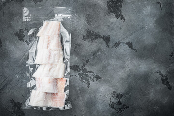 Raw haddock fish skinless, plastic vacuum packaged, on gray background, top view with copy space...