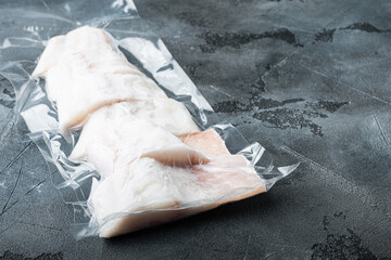 Raw haddock fish skinless, plastic vacuum packaged, on gray background with copy space for text
