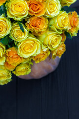 bouquet of yellow roses and pumpkin on black wooden board. Beautiful yellow roses. Autumn decor