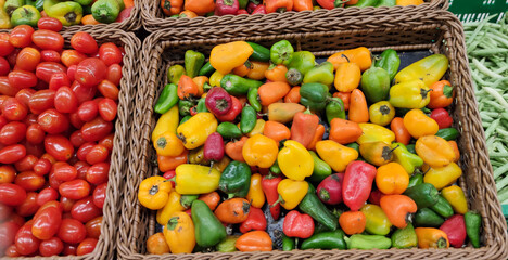 Colorful mini peppers exposed in wooden baskets for sale in supermarket.