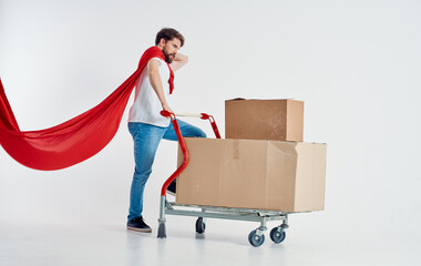 courier with cardboard boxes in cargo trolley and red superhero cloak