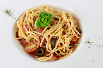 Spaghetti with pesto sauce on white disk.