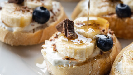 Sweet bruschetta with banana and chocolate pouring with maple syrup, homemade banana dessert